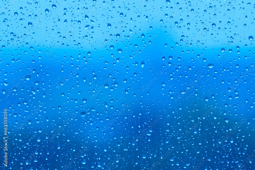 Water drops on glass surface over blurry colored background
