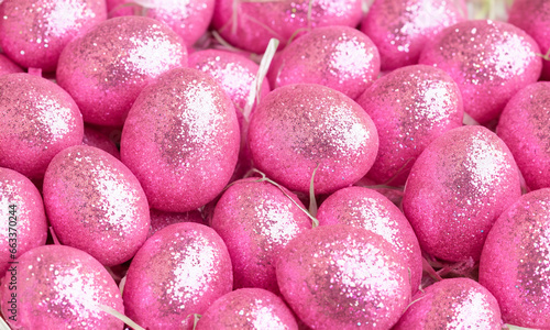 Easter eggs painted pink with glitter, background of holiday symbols