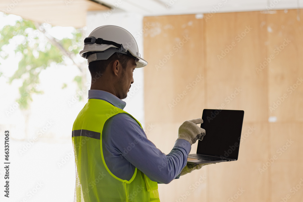 Asian construction worker using laptop at the construction site, industrial building design project concept. Asian construction worker using laptop at the construction site, industrial building design project concept.
