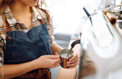 An experienced female bartender prepares a hot drink. A woman in an apron behind the bar prepares fresh coffee. Takeaway food. Professional coffee making.