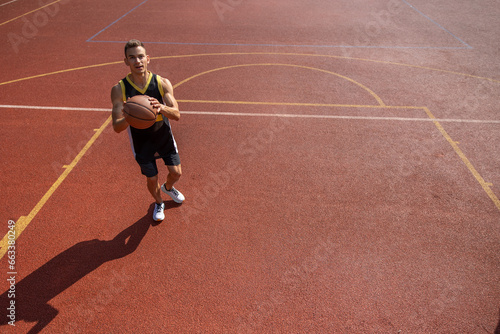 Male sportsman playing basketball throwing ball at playground.