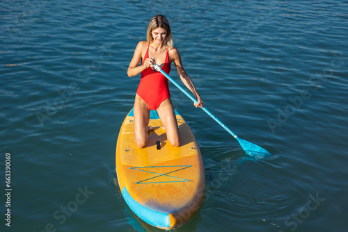 Young woman supsurfing in ocean.