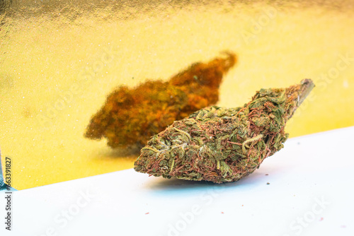 Bola de marihuana sobre una superficie blanca con un fondo dorado reflejante photo