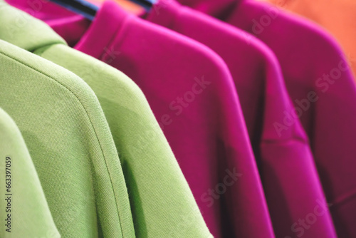 Fashion hoodie clothes on clothing rack Closeup of rainbow color choice female wear on hangers in a clothing store closet Summer home wardrobe.