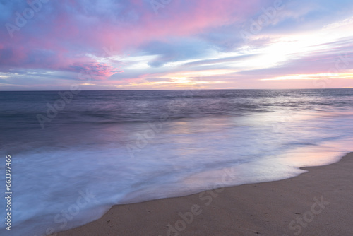 Fototapeta Naklejka Na Ścianę i Meble -  Sunset on sandy beach with ocean waves and colorful sky and clouds, Algarve, Portugal