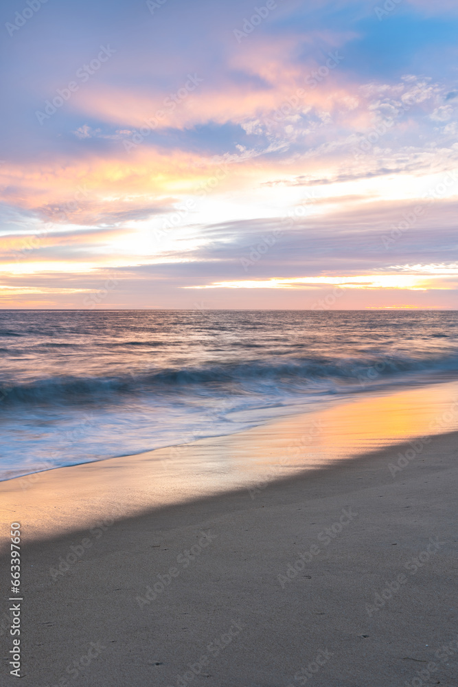 Sunset on sandy beach with ocean waves and colorful sky and clouds, Algarve, Portugal Sunset on sandy beach with ocean waves and colorful sky and clouds, Algarve, Portugal