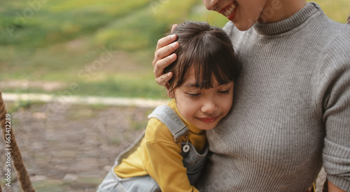 Mother and daughter relax at the park and hug each other.