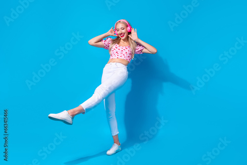 Fototapeta Naklejka Na Ścianę i Meble -  Full body photo of pretty young girl earphones dancing step promo wear trendy pink cherry print outfit isolated on blue color background
