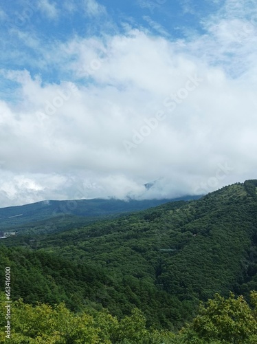 Mountains in clouds at sunrise in summer. Aerial view of mountain peak with green trees in nagano japan.