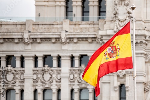 Flag of Spain flying in the wind in front of the Madrid city hall building