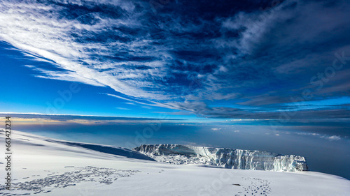 Clouds and blue sky above the snow covered summint of Mount Kilimanjaro