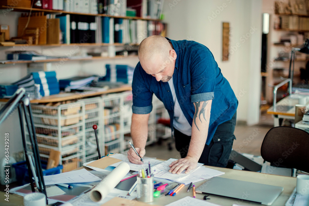 Middle aged Caucasian architect working on building plans in a modern company office Middle aged Caucasian architect working on building plans in a modern company office