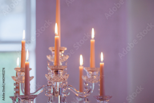 A transparent candelabra sparkling with eight elegant white candles decorates a luxurious wedding banquet hall, creating a romantic and sophisticated atmosphere of the celebration.