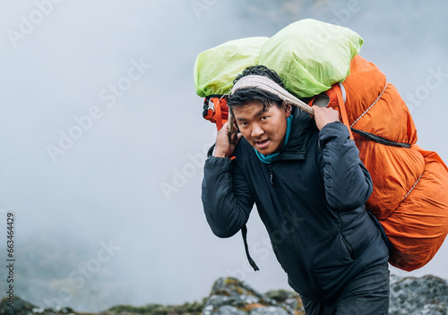 Photos Portrait of strong Sherpa man working as porter carrying a huge cargo with traditional method on forehead