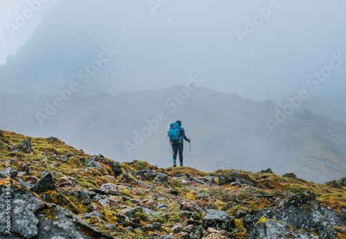 Lonely woman with backpack and trekking poles going by mountain route during Makalu Barun National Park near Tuli Kharka settlement trek in Nepal. Mountain hiking and active people concept image.