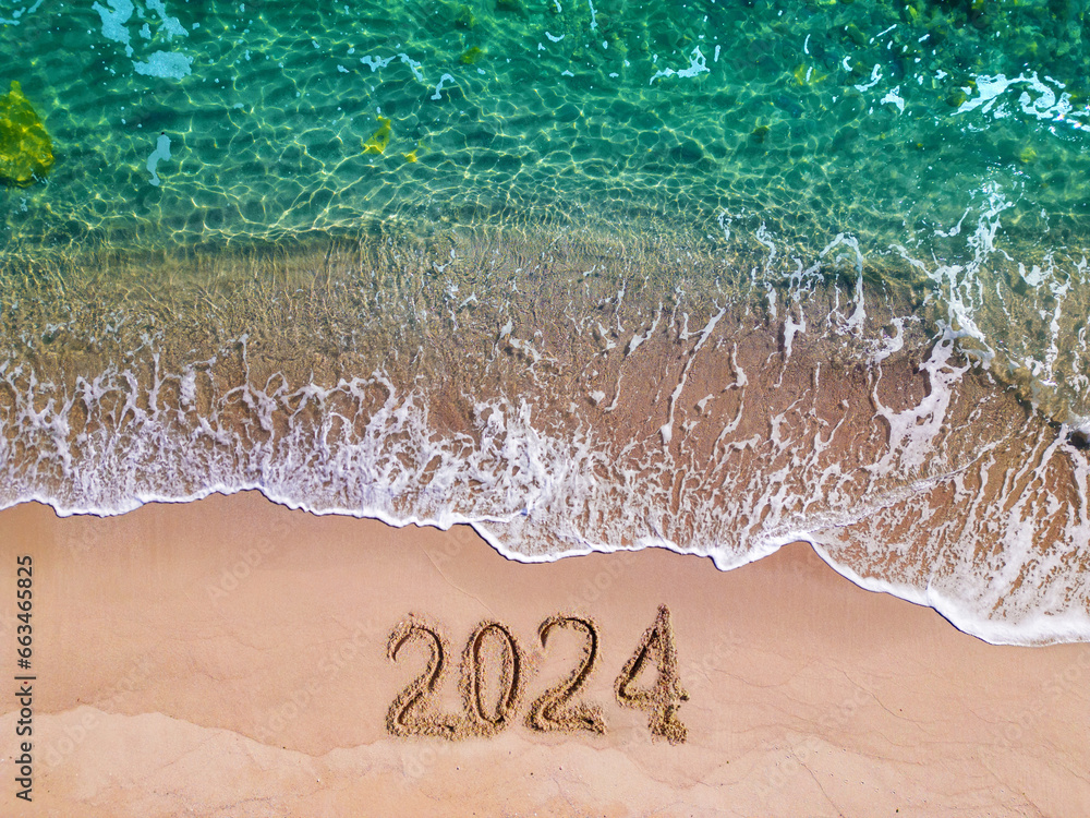2024 year written on sandy beach sea at sunny day - obrazy, fototapety, plakaty 