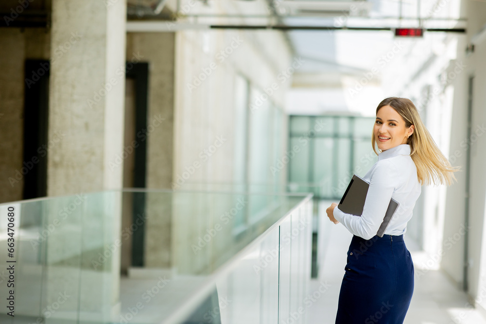 Young woman with digital tablet walking in the modern office hallway Young woman with digital tablet walking in the modern office hallway