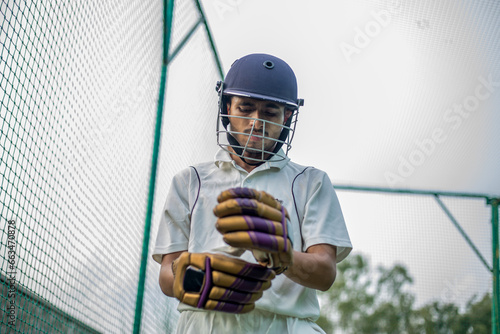 Low angle shot of Cricket player wearing hand gloves to do practice in cricket nets. photo