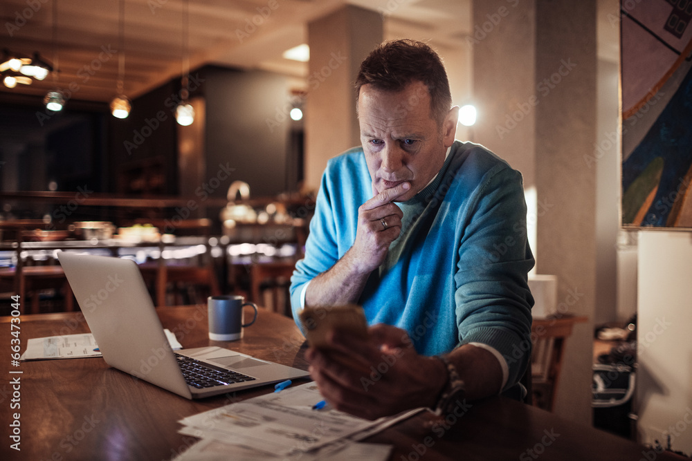 Middle aged man going over financials with a smartphone at home during night Middle aged man going over financials with a smartphone at home during night