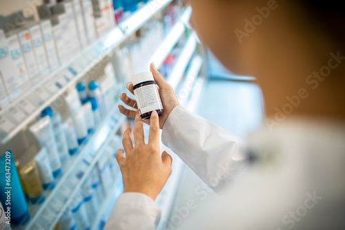 Close up of a female pharmacist reading medication labels at the drugstore photo