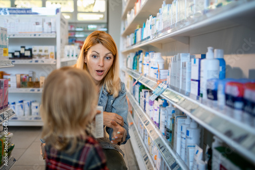 Young mother and daughter browsing the shelfs of a drugstore photo