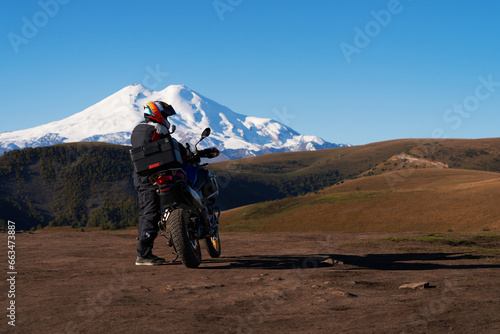 Motorcycle tourism. A biker on the background of a snow-covered volcano. A luggage box is attached to the back of the bike. Copy space