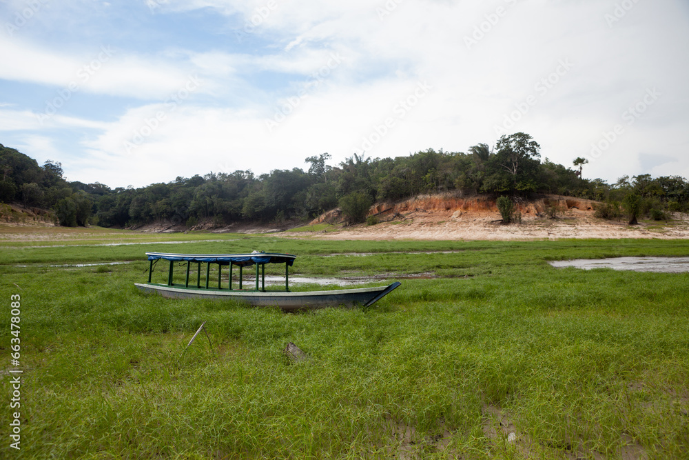 Boat stranded on dry river in extreme drought in the Amazon Rainforest, the largest tropical forest in the world. Concept of climate change, global warming, environment, ecology, disaster, weather. Boat stranded on dry river in extreme drought in the Amazon Rainforest, the largest tropical forest in the world. Concept of climate change, global warming, environment, ecology, disaster, weather.