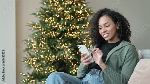 Young woman using smartphone at home during Christmas holiday, Student girl texting on mobile phone indoors, Connection, online shopping, winter lifestyle concept
