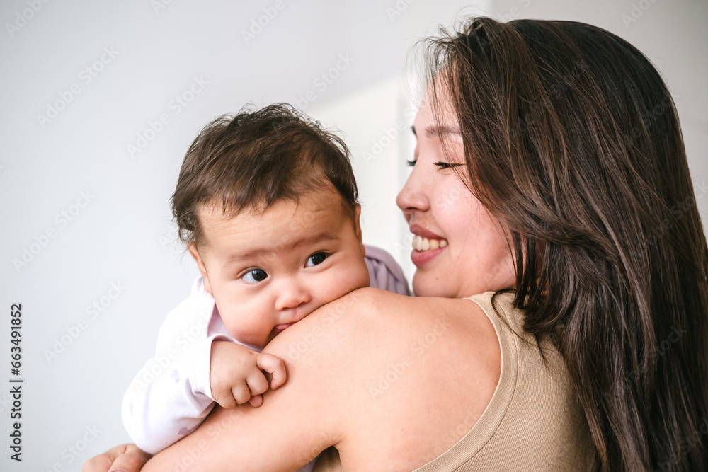 Young asian mother holding little baby girl and smiling Young asian mother holding little baby girl and smiling