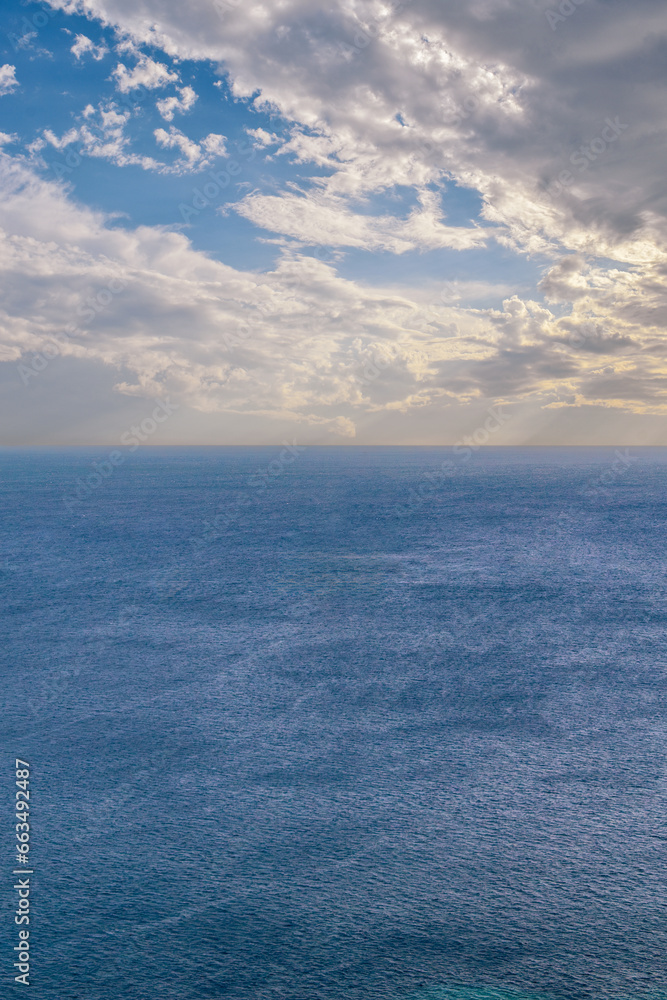 Obraz premium Blue sea with blue sky with clouds, vertical seascape