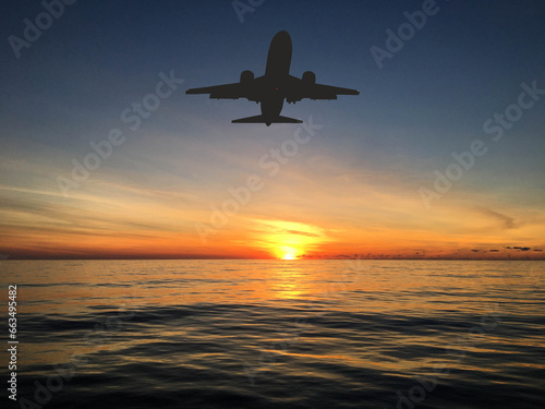 Silhouette of a holiday jet approaching a holiday resort over the sea at sunrise. Travel concept.
