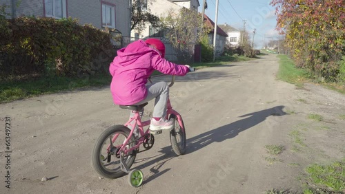 little girl pedaling a bicycle,a child sits on a bicycle in the fall and spins the pedals, slippage of the bicycle wheels