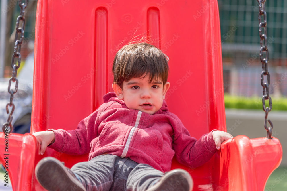 Little boy swinging at the playground in the park. Little boy swinging at the playground in the park.