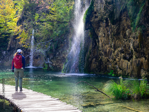 person walking by a waterfall in the plitvice lakes national park