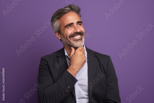 Cheerful mature man looking at camera and smiling while standing against purple background