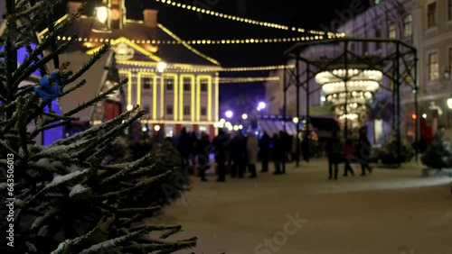 Street Christmas decorations create a festive mood. Large crowd of people from all over the world visiting the Christmas Capital. Beautiful Nordic country in winter, Estonia. Falling snow flakes.