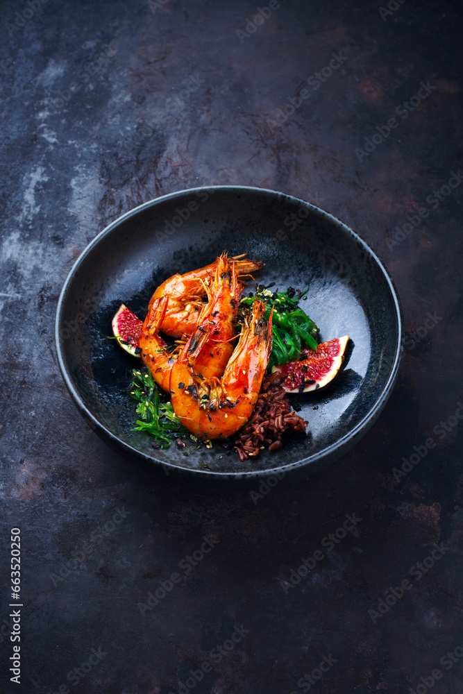 Traditional fried king prawns with fig pieces, brown rice and wakame served as close-up on a design bowl with text space Traditional fried king prawns with fig pieces, brown rice and wakame served as close-up on a design bowl with text space