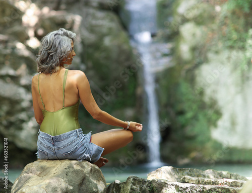 фотографія Religious yoga sitting and praying in nature near to waterfall.