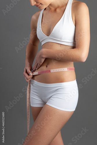 Model in studio taking body measurements seeking weight loss and nutrition, size reduction, diet and health.