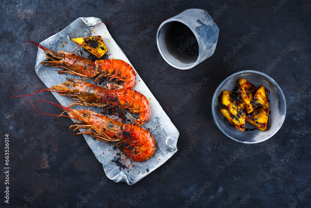 Traditional fried king prawns with pineapple pieces and black salt served as top view on a design tray with text space Traditional fried king prawns with pineapple pieces and black salt served as top view on a design tray with text space
