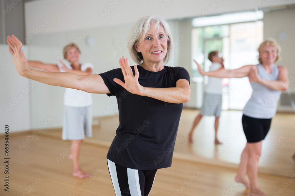 Mature active woman dancing during group training practices energetic swing