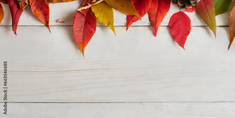 top border of autumn foliage with other fall decorations on white rustic wooden boards 