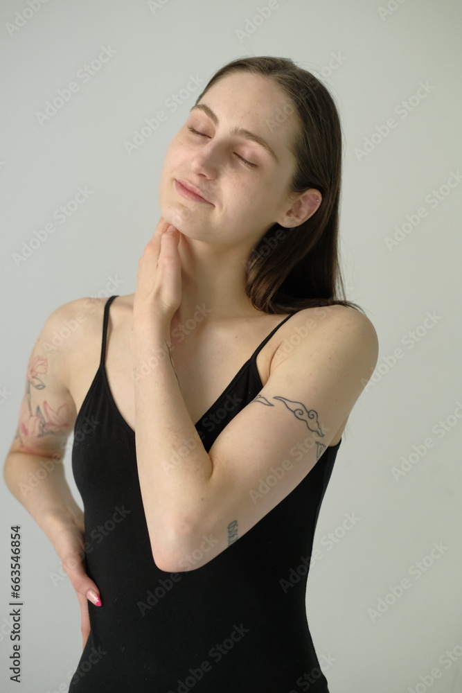 Fototapeta premium Young brunette girl in black swimming bodysuit on a white background
