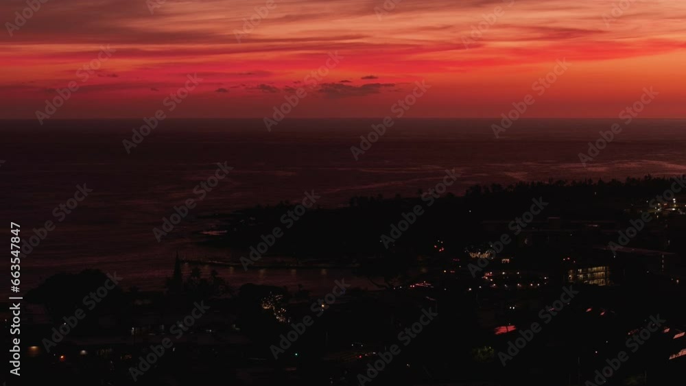 Aerial Kona Hawaii city dark red sunset cityscape. Big Island. Luxury exclusive resorts homes on coast with tropical landscape. Economy is tourism based. Water and tropical beach recreation and fun. Aerial Kona Hawaii city dark red sunset cityscape. Big Island. Luxury exclusive resorts homes on coast with tropical landscape. Economy is tourism based. Water and tropical beach recreation and fun.