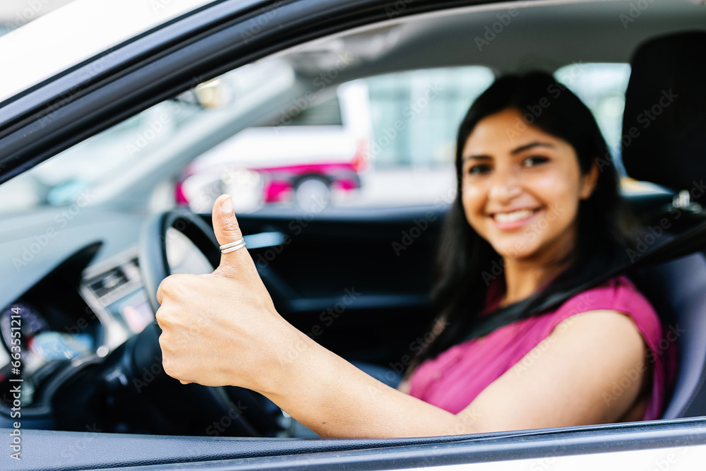 Joyful portrait of young indian woman with the seat belt on, sitting on driver's seat in her car. Focus on hand. Joyful portrait of young indian woman with the seat belt on, sitting on driver's seat in her car. Focus on hand.