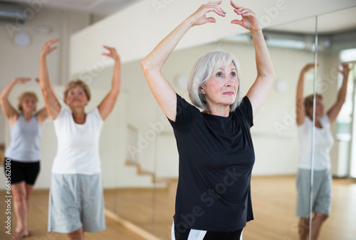 Portrait of a mature woman in a group class, standing at the 5th position of the ballet stand in a dance studio