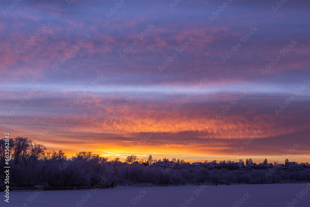 Idyllic sunset with a colorful cirrus clouds above a frozen river.