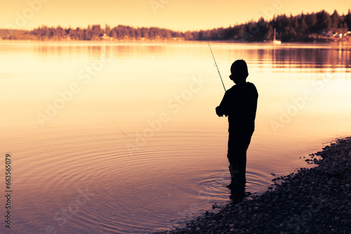 silhouette of little boy fishing on a lake 