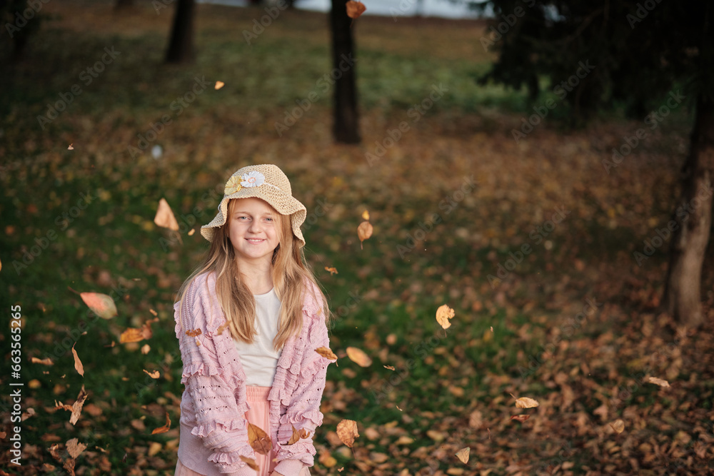 Obraz premium A happy joyful girl throwing a fallen leaves in the autumn park.