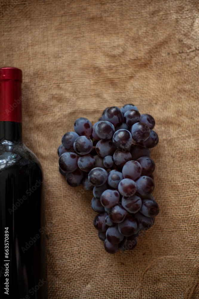 Moldovan wine. Bunch of grapes and a bottle of red wine on burlap. View from above. Copy space.